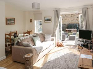 een woonkamer met een bank en een televisie bij Ramblers Cottage in Glanton