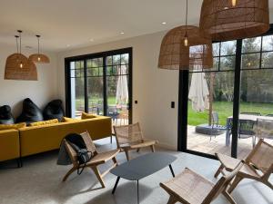 a living room with a yellow couch and chairs at Villa Lombardière in Gujan-Mestras