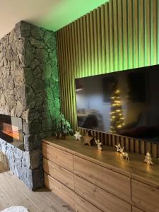 a living room with a tv and a stone wall at Kamzík 51 Donovaly in Donovaly
