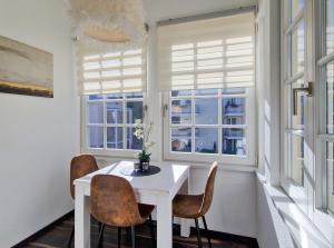a dining room with a white table and chairs and windows at Brise Villa Emmi App 03 in Heringsdorf