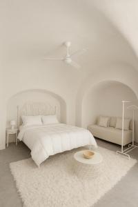 um quarto branco com uma cama e uma mesa em Unique small stonehouse at Thira em Megalokhori