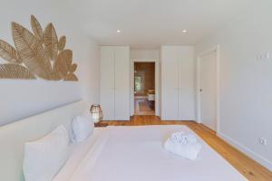 a white bedroom with a large white bed with two pillows at Quinta View Apartment, By Home Match in Setúbal
