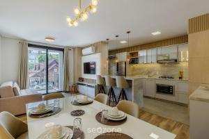 a kitchen and dining room with a table and chairs at Acomodações modernas e completas no centro turístico de Gramado - CBGs in Gramado
