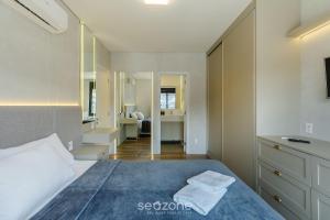 a bedroom with a bed with a blue blanket at Acomodações modernas e completas no centro turístico de Gramado - CBGs in Gramado