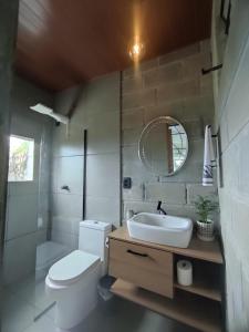 Un baño con inodoro, lavabo y espejo. en Morada do Altíssimo, en Florianópolis