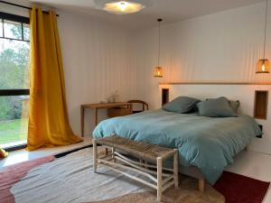 a bedroom with a bed with a bench and a window at Villa Lombardière in Gujan-Mestras +7 photos