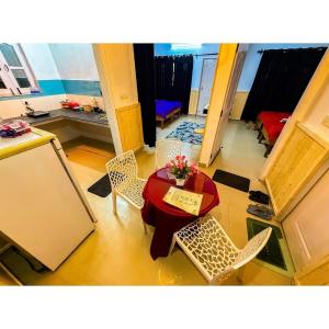 une pièce avec une table et des chaises avec une table et des chaises rouges dans l'établissement Family & Couples Studio Kitchen, 2 King Beds, à Dehradun