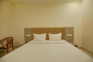 a large white bed with two pillows and a chair at Hotel Melano Ambala Chandigarh Rd Zirakpur SkyJumper park in Zirakpur