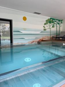 a swimming pool in a house with a painting on the wall at Villa Lombardière in Gujan-Mestras
