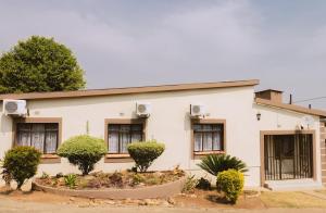 a white house with bushes in front of it at The Treat Manzini in Manzini