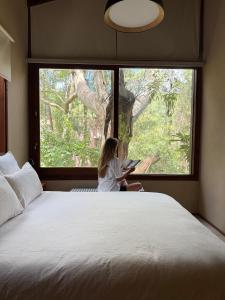 een klein meisje dat voor een groot raam zit bij Casa Azul in Mar de las Pampas