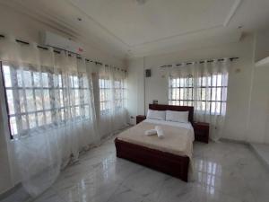 Un dormitorio con una cama en una habitación con ventanas. en Douce vie, en Cotonou