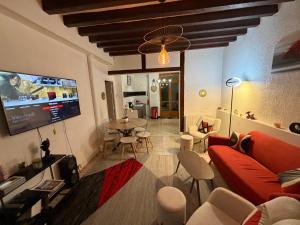 ein Wohnzimmer mit einem roten Sofa und einem Flachbildfernseher in der Unterkunft Charmante maison de ville in Bléneau