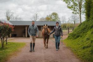 un uomo e una donna che portano a spasso un cavallo lungo una strada sterrata di Parcel Tiny House I Pommiers a Landes-sur-Ajon