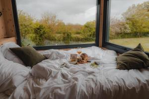 un letto con un piumone bianco con un piatto di cibo e una bevanda di Parcel Tiny House I Pommiers a Landes-sur-Ajon