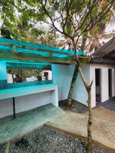 a house with a blue roof and a tree at Ryo hostel in Ahangama