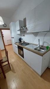 una cucina con mobili bianchi, un lavello e una stufa di Casa Mamus 2 a Pescara
