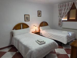 twee bedden in een kamer met witte lakens bij Alojamiento Rural Dilamor in El Picazo