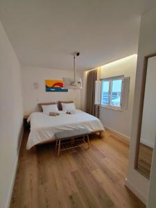 una camera da letto con un letto bianco e un pavimento in legno di Hostel Rosa a São Pedro de Muel Altre 22 foto