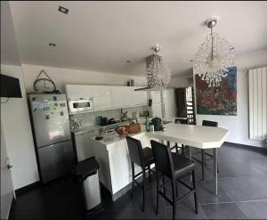 kuchnia z białym stołem i krzesłami oraz lodówką w obiekcie Chambre avec salle de bain et terrasse dans un maison chaleureuse w mieście Nanterre +4 zdjęcia