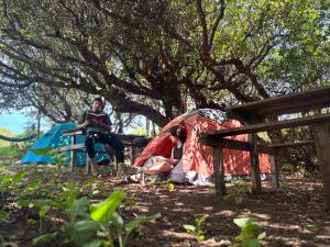 Un hombre y una mujer sentados frente a una tienda de campaña. en Muelle del Tiempo Camping, en Quilán