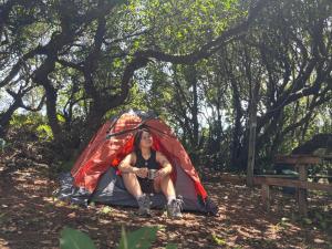 un hombre y una mujer sentados en una tienda en Muelle del Tiempo Camping, en Quilán