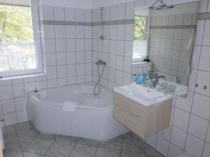 ein weißes Badezimmer mit einer Badewanne und einem Waschbecken in der Unterkunft Alte Waldmühle in Wernigerode