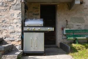 阿尔佩德维洛Casa Cantone Devero-baita storica con balcone e giardino, posizione comoda e soleggiata- spazio biciclette的建筑物前设有带烤架的户外烤炉