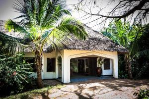 a house with a palm tree in front of it at Fumba Beach Lodge in Fumba