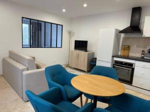 a living room with a table and blue chairs at Le Prestige - T2 Neuf et Equipé in Évreux