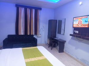 Un dormitorio con una cama y un televisor de pantalla plana. en Ashirwad Lucknow, en Lucknow