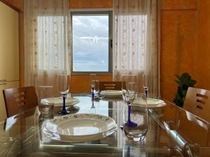 una sala da pranzo con tavolo in vetro, sedie e finestra di Hana's Apartment a Durrës