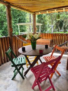 a table and chairs on a porch with a table and flowers at Chalé 01 maritacas in Cunha