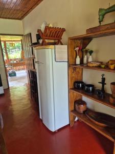 a kitchen with a white refrigerator and wooden shelves at Chalé 01 maritacas in Cunha +105 photos