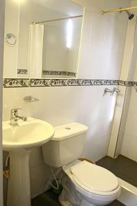 a white bathroom with a toilet and a sink at Hotel Villa Karina in Bogotá
