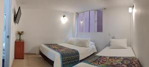a small room with two beds and a window at Hotel Villa Karina in Bogotá