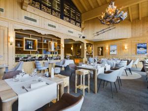 a restaurant with white tables and chairs and a chandelier at Chalet RoyAlp Hôtel & Spa in Villars-sur-Ollon