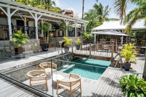 a resort pool with chairs and a table at La Villa Hibiscus, Saint Martin in Cul de Sac