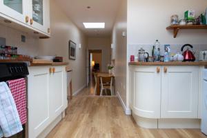 een keuken met witte kasten en een houten vloer bij Moir Cottage in Portpatrick +10 foto's
