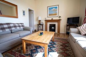 een woonkamer met een bank en een salontafel bij Moir Cottage in Portpatrick