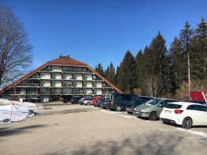 ein großes Gebäude mit auf einem Parkplatz abgestellten Autos in der Unterkunft Vaste appartement de montagne in Métabief