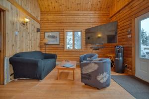 a living room with two chairs and a flat screen tv at Chalet Saumon with Private SPA for 16 Guests , Skiing in Saint-Paul-de-Montminy
