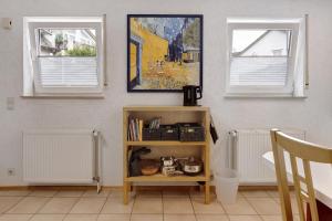 una libreria in una stanza con due finestre di Ferienwohnung Im Bohrer a Donaueschingen