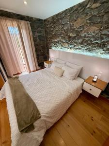 阿科达卡列塔Casa do terno com piscina的一间卧室，配有一张大床和一堵石墙