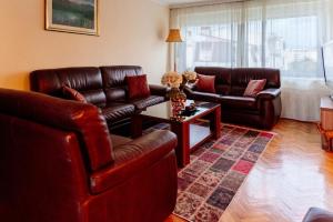 sala de estar con muebles de cuero y mesa en Milenijum apartman, en Podgorica