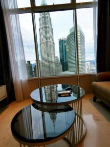 a living room with a glass table and a large window at Sky Suites KLCC By Elite Stay in Kuala Lumpur