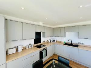 フェリックストウにある2A Hamilton Roadの白いキャビネットと黒の電化製品が備わるキッチン