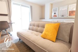 Una sala de estar con un sofá con una almohada amarilla. en WeeklyHouse Schildkrote, en Otsu