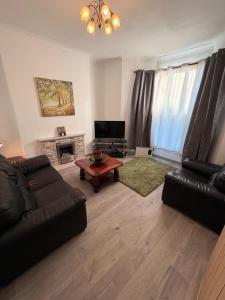 ein Wohnzimmer mit Sofa und Tisch in der Unterkunft A cozy, comfortable, calm house perfect for groups in Swansea