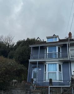 ein blaues Haus mit einer Veranda und einem Balkon in der Unterkunft A cozy, comfortable, calm house perfect for groups in Swansea